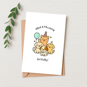May include: A white greeting card with a brown envelope features a cartoon illustration of a cat and three dogs. The cat wears a party hat and holds a balloon. The text reads "Have a pawsome Birthday!" in black lettering.