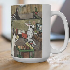May include: White ceramic coffee mug featuring a whimsical illustration of rabbits in an office setting. One rabbit is at a computer, another is reading documents, and a third is in the background. The mug has a large handle and a glossy finish.