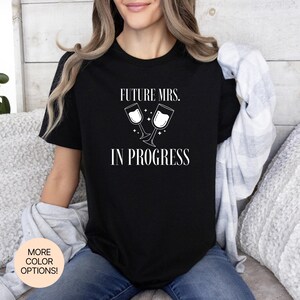 未来の奥様、進行中！Tシャツは豊富なカラー＆サイズをご用意。結婚式の準備、コーヒーデート、カウントダウンにぴったりのエンゲージメントTシャツです。