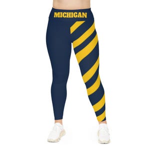 May include: Navy blue leggings with a yellow diagonal stripe pattern on the right leg. The waistband has the word "MICHIGAN" in yellow letters.