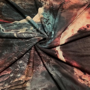 May include: A piece of fabric featuring an abstract print with swirling patterns of deep black, dark teal, and warm orange-red tones. The material is gathered in the center, creating folds that highlight the textured, marbled appearance of the design.
