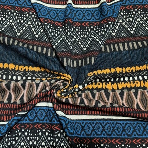 May include: Striped fabric with a geometric pattern in shades of brown, blue, white, and yellow. The fabric has a textured surface and a woven look.