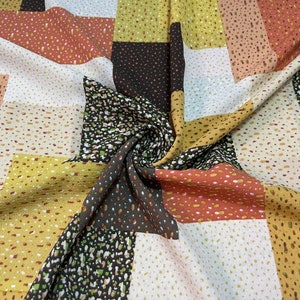 以下が含まれることがあります： 異なる色と模様の正方形が組み合わされたパッチワークデザインの生地。生地は柔らかく軽量な素材でできており、上品な光沢があります。生地の色は、茶色、ベージュ、黄色、オレンジなどです。生地は、衣服、アクセサリー、インテリアなど、さまざまな縫製プロジェクトに最適です。