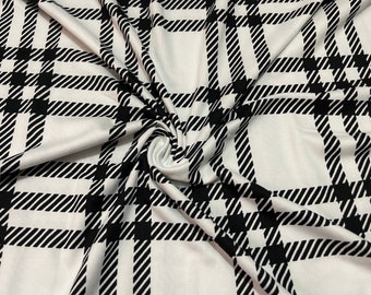 May include: White fabric with a black and white plaid pattern. The fabric is wrinkled and has a soft, stretchy texture.