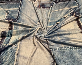 May include: A fabric with a denim print, featuring various shades of blue and white. The design mimics the look of denim jeans, with visible stitching and distressed details. The fabric is folded, creating a swirling pattern.