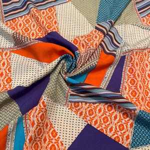 May include: A fabric featuring a vibrant patchwork design with geometric shapes in bright orange, deep purple, and teal. The pattern includes sections of intricate white and black dotted textures, striped bands, and bold orange floral-like motifs.