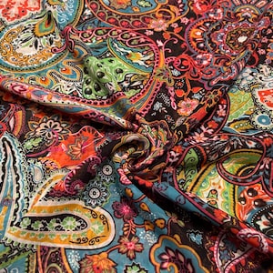 May include: A vibrant fabric with a paisley pattern in a variety of colors. The design features intricate floral and teardrop motifs in shades of orange, teal, green, and pink against a black background. The fabric is folded, showing its texture and detail.