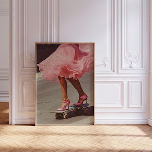 May include: A framed wall art print depicting a person wearing a voluminous pink tulle skirt and matching pink high-heeled pumps while riding a skateboard on a paved surface. The image captures the lower half of the figure in motion.
