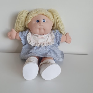 May include: A white ceramic mug with a black handle and the text "But First, Coffee" in a handwritten style. The mug is on a white surface. The mug is approximately 4 inches tall.