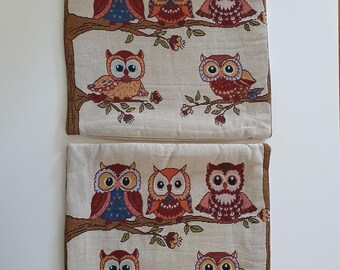 May include: Two cushion covers with embroidered owl designs. Each cover has a beige background with brown branches and colourful owls in various poses. The owls have blue, orange, and red details.