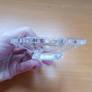 May include: A clear glass bowl with a scalloped edge and a star-shaped base. The bowl is empty and appears to be made of crystal.
