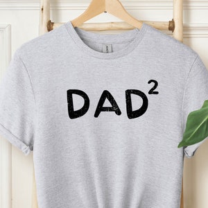 May include: Gray t-shirt with the text "DAD²" printed in black.