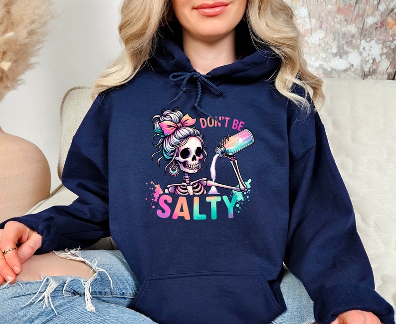 May include: A navy blue hoodie with a colorful graphic of a skeleton with a bun in her hair pouring salt from a shaker. The text "Don't Be Salty" is printed below the graphic.