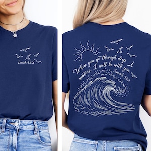 May include: Navy blue t-shirt with white text and graphics. The front features flying birds and "Isaiah 43:2". The back displays a sun, birds, a wave, and the text "When you go through deep waters. I will be with you. Isaiah 43:2."