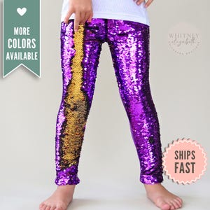 May include: Purple and gold sequin leggings. The leggings have a vertical gold stripe down the front and are otherwise purple. The image also includes a white top and the text "More Colors Available" and "Ships Fast".