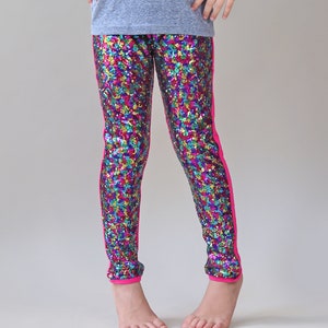 Peut inclure: Leggings multicolores à paillettes avec des bandes latérales roses. Les leggings sont faits d'un tissu extensible et ont une coupe confortable.