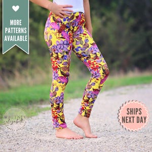 May include: Yellow leggings with a vibrant floral pattern in shades of purple, red, and brown. The leggings feature a high waist and a fitted design. The text "MORE PATTERNS AVAILABLE" is visible.