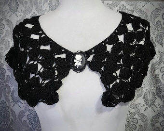 Puede incluir: Collar de crochet negro con un camafeo con una silueta blanca de una rosa.