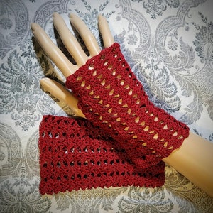 May include: A pair of red crocheted fingerless gloves with a lacy pattern.