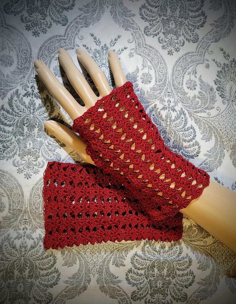 May include: A pair of red crocheted fingerless gloves with a lacy pattern.