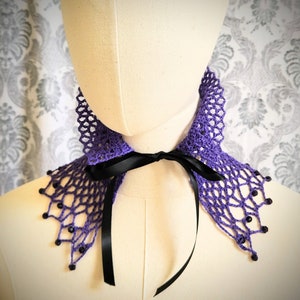 May include: Purple crochet collar with black ribbon ties and beaded accents.