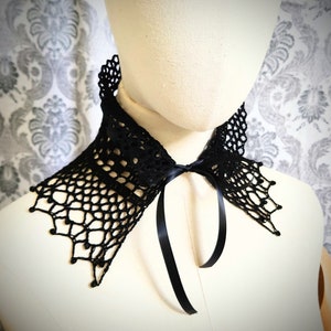 May include: Black crochet collar with a black satin ribbon tie. The collar features a delicate lace pattern and a scalloped edge.