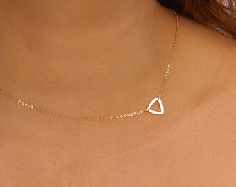 May include: A delicate gold chain necklace with a simple triangle pendant.