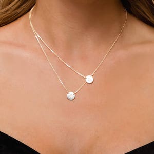 May include: A gold chain necklace with two small round pendants. The pendants are simple and elegant, and the necklace is perfect for everyday wear.