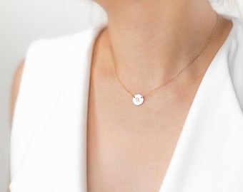 Puede incluir: Un collar de cadena de oro con un pequeño colgante redondo con una sola inicial.