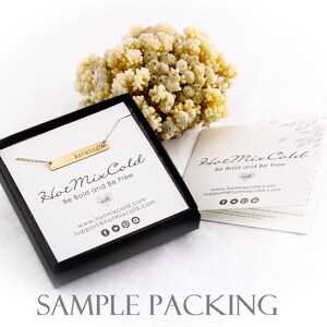 K&ouml;nnte beinhalten: Eine schwarze Schachtel mit einer goldenen Bar-Halskette darin. Die Halskette hat einen kleinen blauen Stein und den Namen "kavanagh" auf der Bar graviert. Die Schachtel tr&auml;gt den Text "Hot Mix Cold Be Bold and Be Free". Die Schachtel steht auf einer wei&szlig;en Oberfl&auml;che.