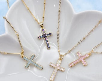May include: Four gold necklaces with different colored cross pendants. The crosses are made of small mosaic tiles in shades of pink, blue, white, and purple.