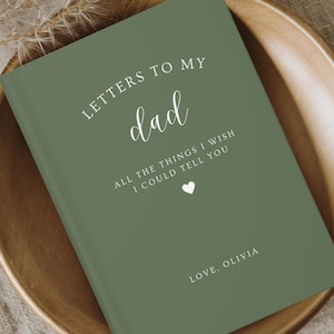 Pode incluir: Um diário verde com o texto "LETTERS TO MY dad ALL THE THINGS I WISH I COULD TELL YOU LOVE, OLIVIA" na capa.