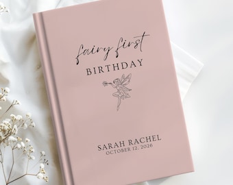 May include: A dusty rose hardcover book with black text that reads Fairy first BIRTHDAY, a line drawing of a fairy, and the name SARAH RACHEL with the date OCTOBER 12, 2026. The book cover has a smooth, matte finish and a clean, centered layout.