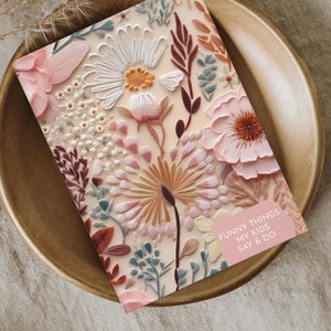 Peut inclure: Un carnet rose et crème avec un motif floral et le texte "Funny Things My Kids Say & Do" sur la couverture.
