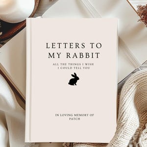 Puede incluir: Un libro de tapa dura crema con el título "LETTERS TO MY RABBIT" en texto negro. El libro presenta el texto "ALL THE THINGS I WISH I COULD TELL YOU" y una silueta de conejo. Está dedicado "IN LOVING MEMORY OF PATCH".