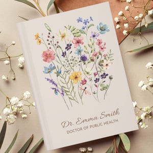 May include: A hardcover journal with a floral watercolor design. The cover features a bouquet of colorful wildflowers in shades of pink, blue, yellow, and purple. The text "Dr. Emma Smith, DOCTOR OF PUBLIC HEALTH" is printed in a serif font.