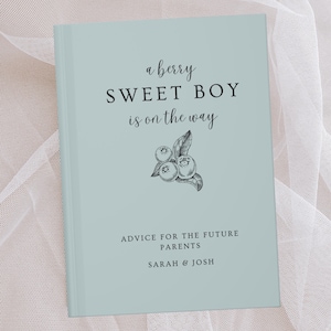 K&ouml;nnte beinhalten: Ein hellblaues Baby-Ratgeberbuch mit dem Text "a berry SWEET BOY is on the way" und einer Blaubeer-Illustration. Das Buch enth&auml;lt auch den Text "ADVICE FOR THE FUTURE PARENTS" und die Namen "SARAH & JOSH".