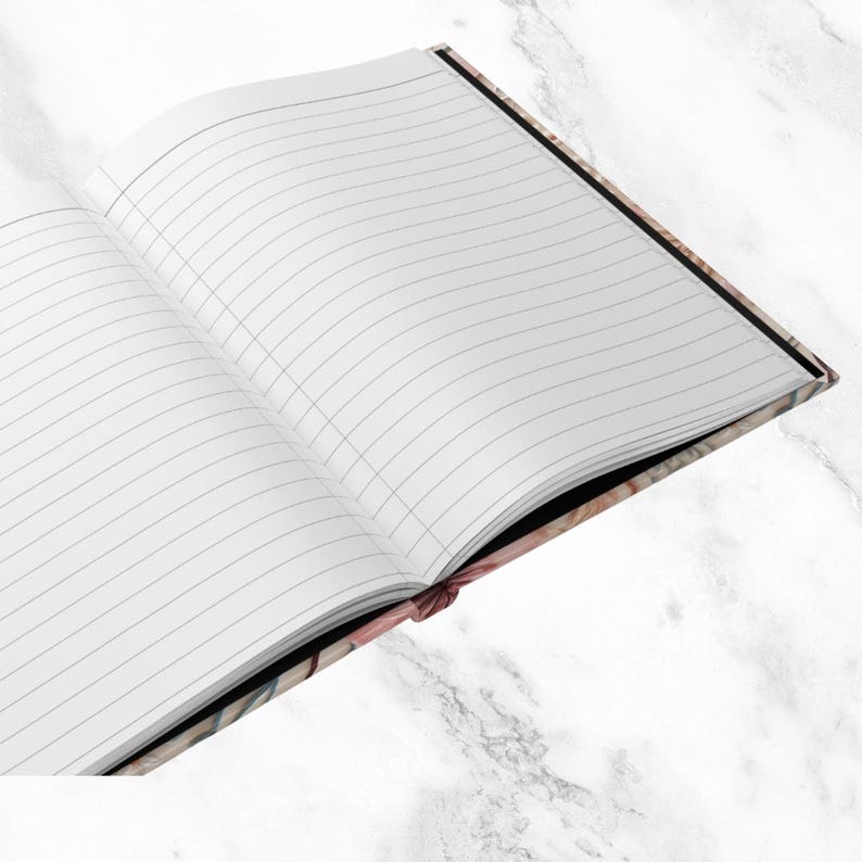 K&ouml;nnte beinhalten: Ein leeres, liniertes Notizbuch mit schwarzem R&uuml;cken und einem bunten, gemusterten Einband. Das Notizbuch ist auf einer leeren Seite ge&ouml;ffnet.