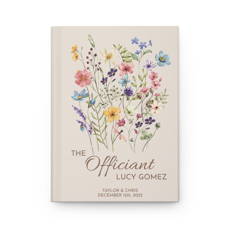 May include: A beige book cover with a floral design in shades of pink, yellow, blue, and green. The text "The Officiant Lucy Gomez" is printed in brown on the cover, along with the names "Taylor & Chris" and the date "December 12th, 2023".
