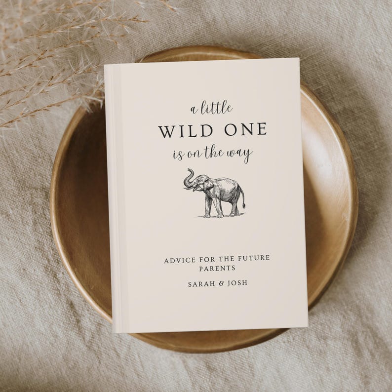 May include: A white book with the text "a little WILD ONE is on the way" and a black and white illustration of an elephant. The text "ADVICE FOR THE FUTURE PARENTS SARAH & JOSH" is printed below the illustration.