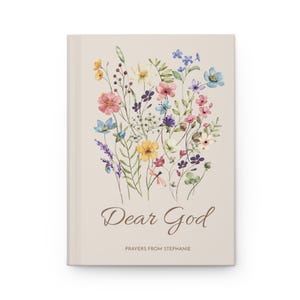 May include: A beige journal with a watercolour floral design. The cover features a bouquet of colourful flowers, including pink, blue, yellow, and purple blooms. The words "Dear God" are written in a script font, with "Prayers from Stephanie" below.
