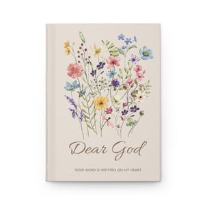 May include: A beige journal with a watercolour floral design. The cover features a bouquet of colourful flowers in shades of pink, yellow, blue, and purple. The words "Dear God" are written in a script font, with the phrase "Your word is written on my heart" below.