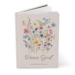 May include: A hardback journal with a beige cover. It features a watercolour floral design in pink, blue, yellow, and purple. The words "Dear God" are written in script, with "Prayers from Stephanie" below.