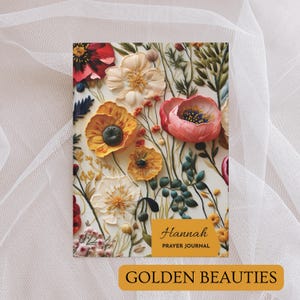 K&ouml;nnte beinhalten: Ein florales Gebetsjournal mit einem Design aus gelben, rosa und wei&szlig;en Blumen. Der Umschlag tr&auml;gt die Aufschrift "Hannah Prayer Journal" und "Golden Beauties".
