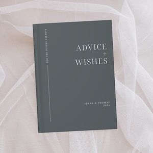 May include: A dark grey hardback journal with the text "Advice + Wishes" in white lettering. The journal is for future parents and has the names "Jenna & Thomas" and the year "2024" printed on the front cover.