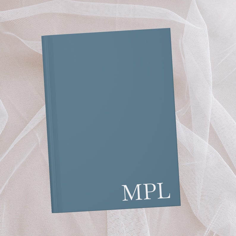 Puede incluir: Un cuaderno de tapa dura azul con las letras "MPL" impresas en blanco en la portada.