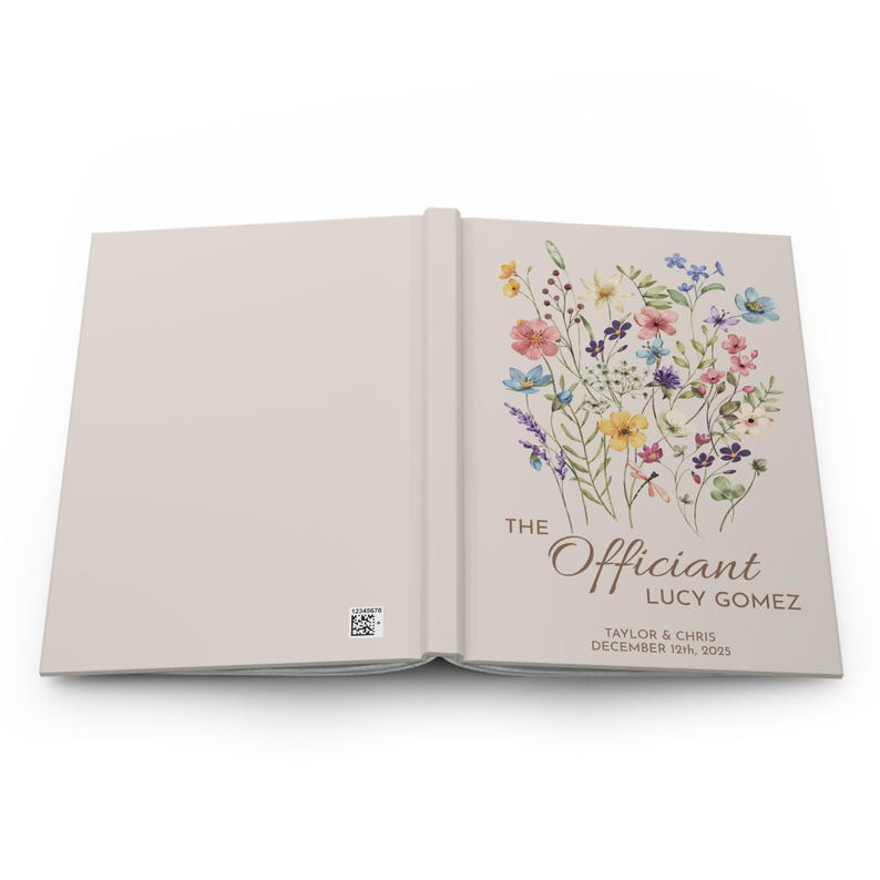 May include: A light beige book with a floral design on the cover. The text "The Officiant Lucy Gomez" is printed on the cover, along with the names "Taylor & Chris" and the date "December 12th, 2025".