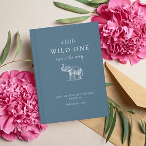 May include: A blue book with the text "a little WILD ONE is on the way" and an illustration of an elephant. The text "ADVICE FOR THE FUTURE PARENTS SARAH & JOSH" is printed below the illustration.