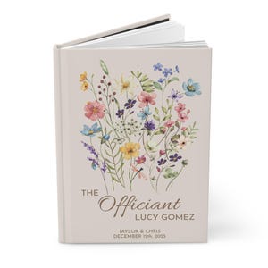 May include: A beige book cover with a floral design in shades of pink, yellow, blue, and green. The text "The Officiant Lucy Gomez" is printed in brown at the bottom of the cover, along with the date "December 12th, 2025".