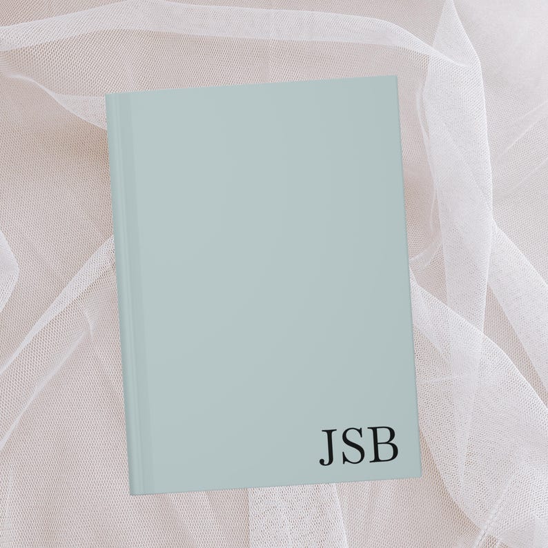 Puede incluir: Un cuaderno azul claro con las iniciales "JSB" impresas en negro en la portada.